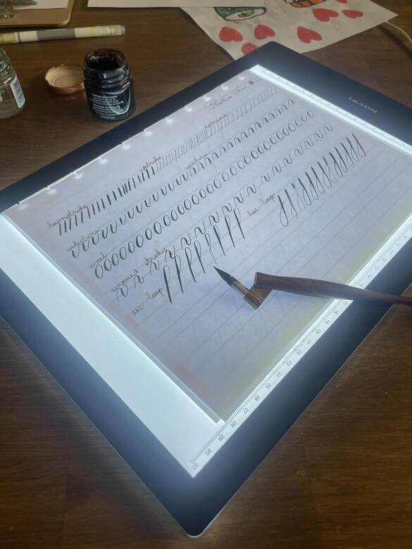 - Calligraphy practice piece written with fountain pen ink. - Handwritten calligraphy lettering on white paper.